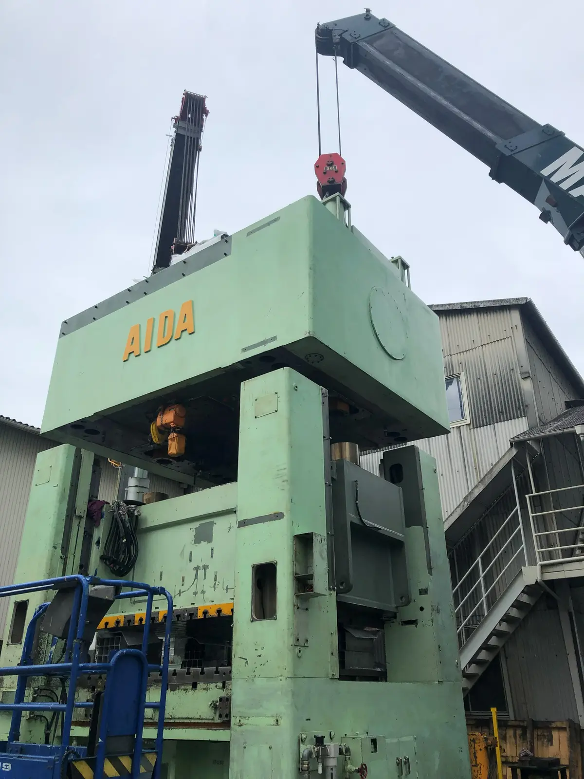 クレーンで吊られたプレス機
